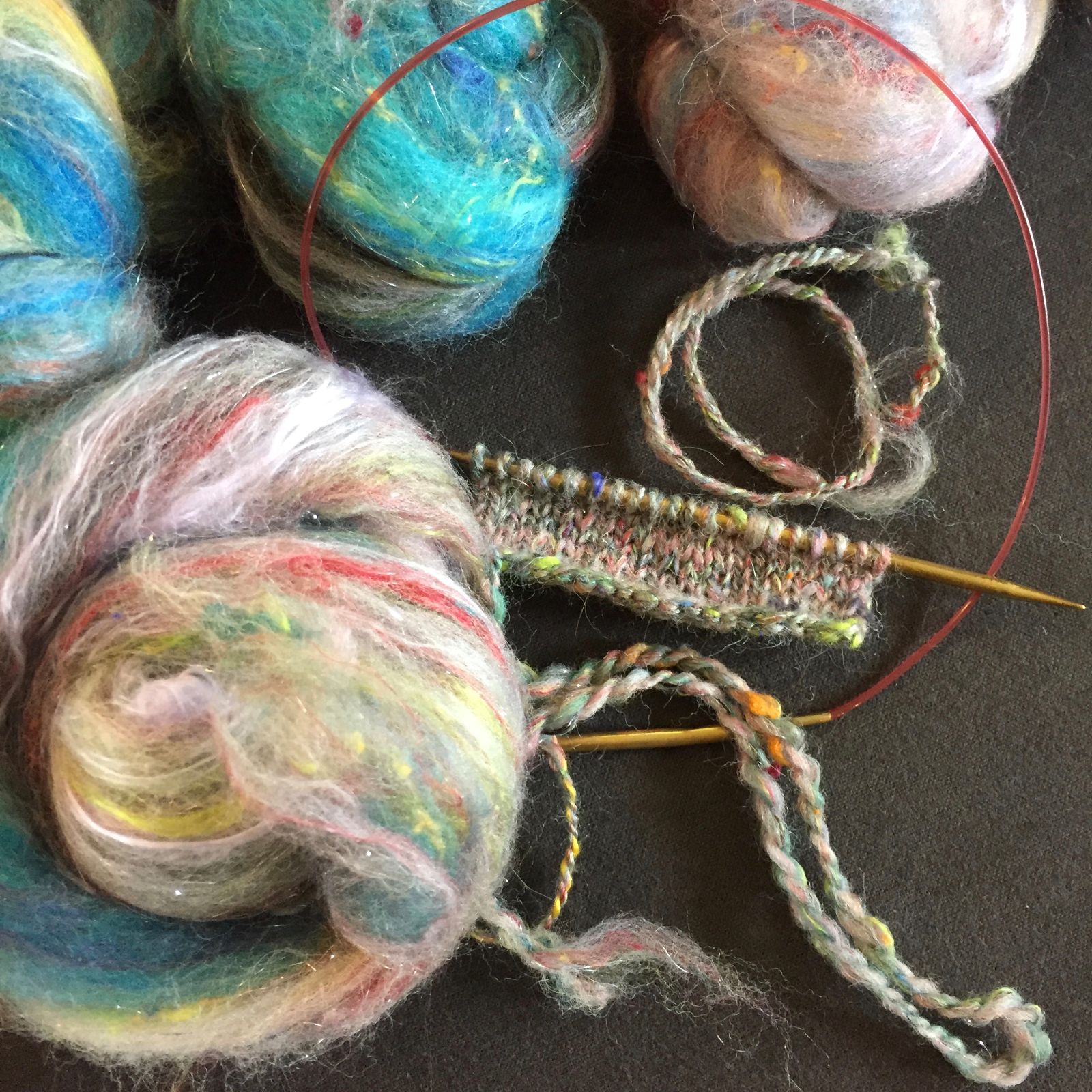 Balls of multicolored yarn with a piece of knitting on circular knitting needles